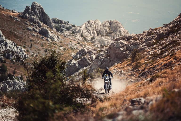 Rider far below jagged limestone peaks