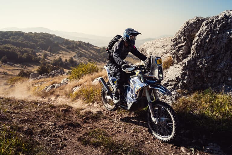 Rider on a rally bike below limestone cliffs