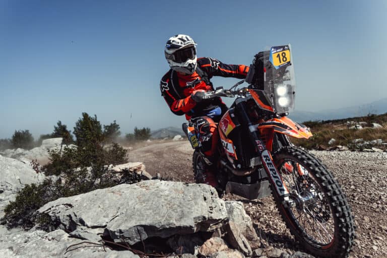 Rider on a rally bike climbing over rocks
