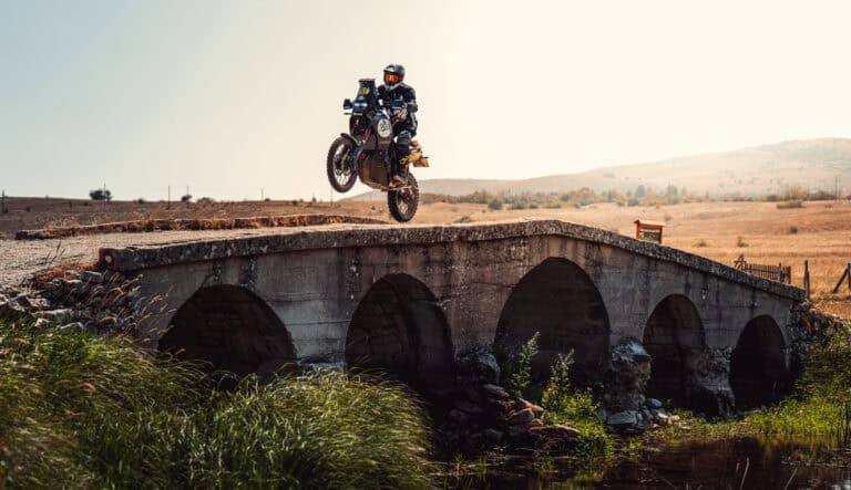 Rider jumping over an old stone bridge