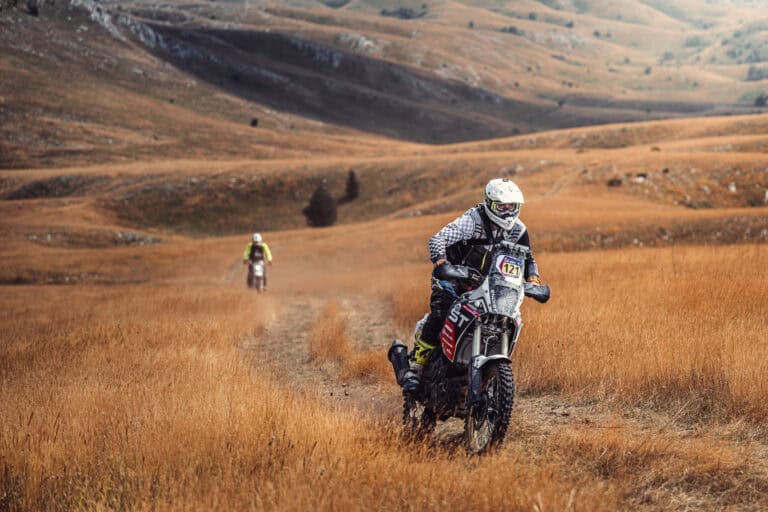 Rider on a dusty track across a golden plateau