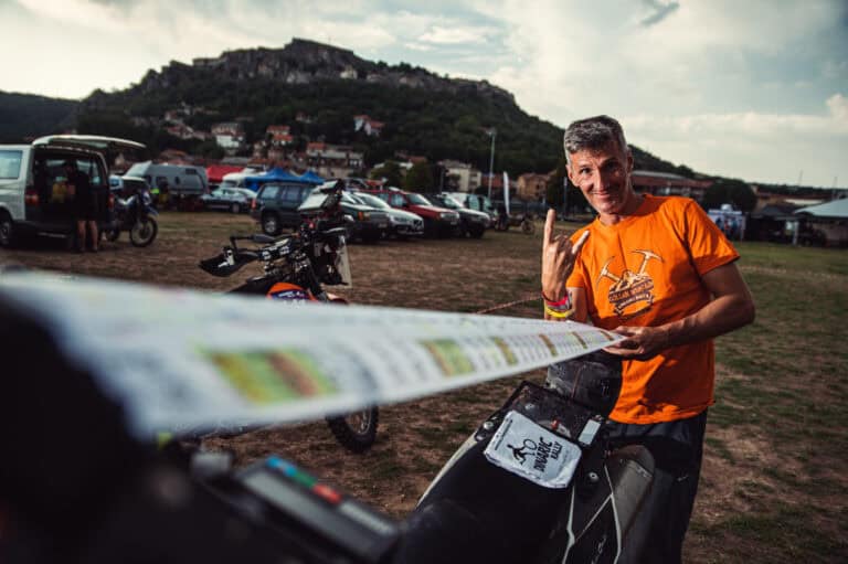 Rider in an orange shirt studying a roadbook roll
