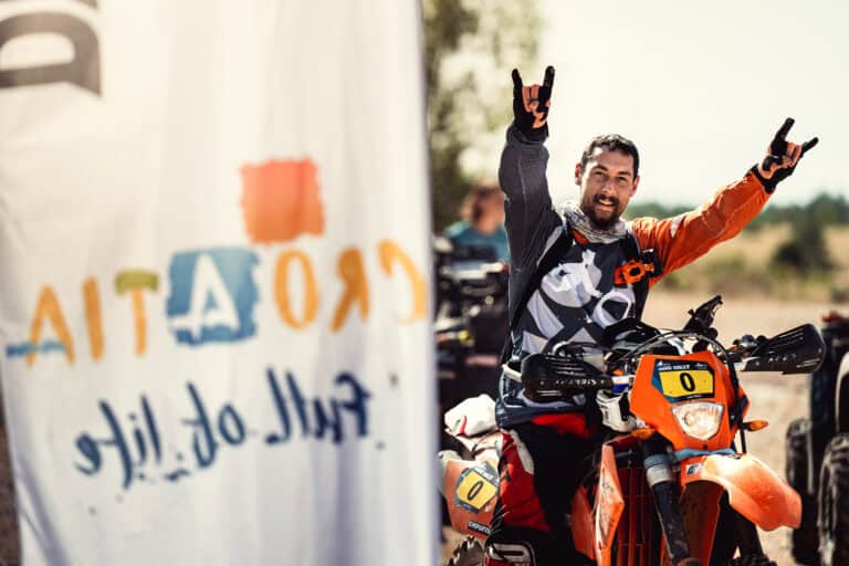Rider cheering at the finish next to a Croatia flag