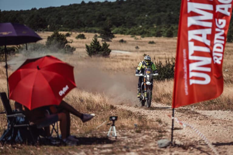 Rider passing a spectator under a red umbrella