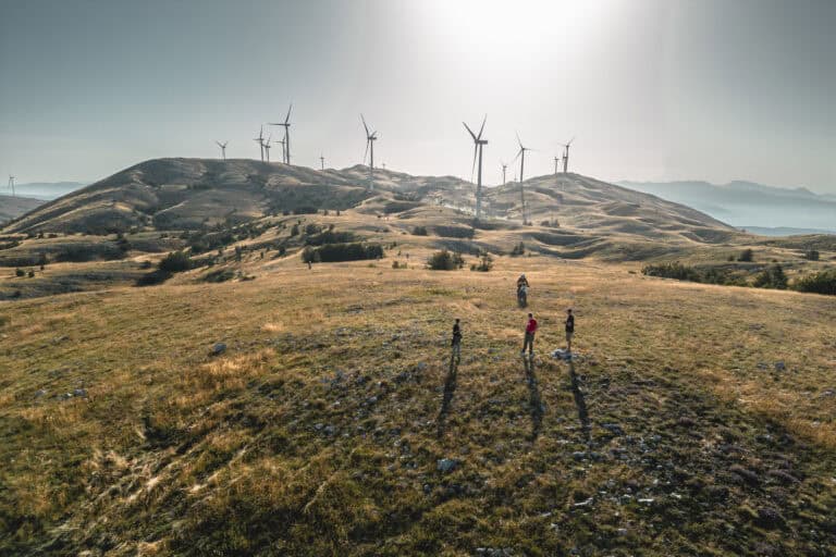Wind turbines on a grassy ridge above the rally route