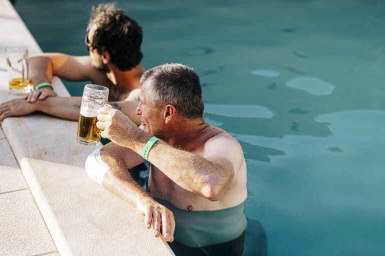 Two riders relaxing with drinks at the camp pool