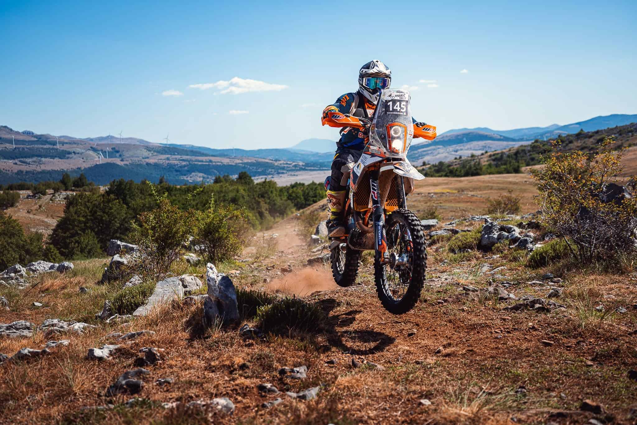 Pilota di rally in salto su una pista rocciosa sopra un lago