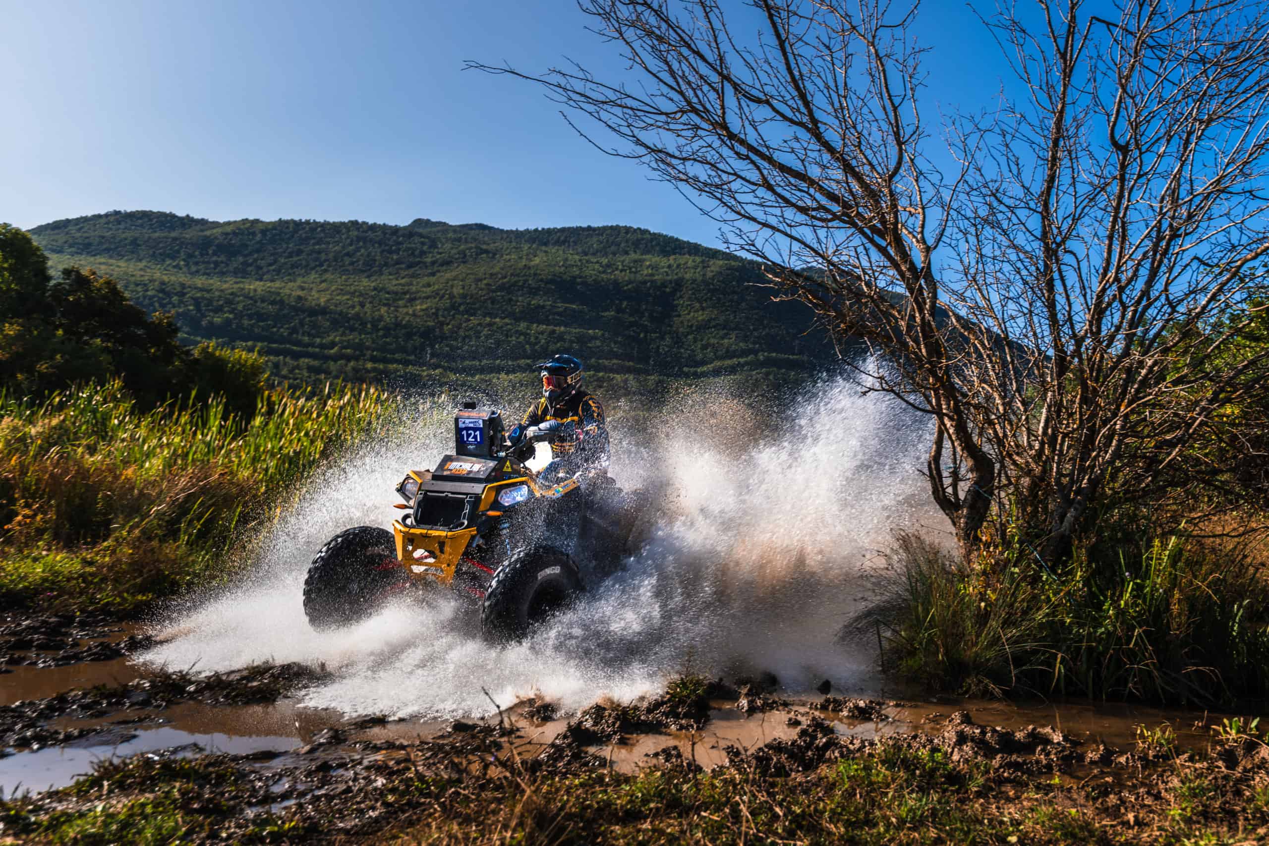 Quad che attraversa un torrente su una pista di montagna