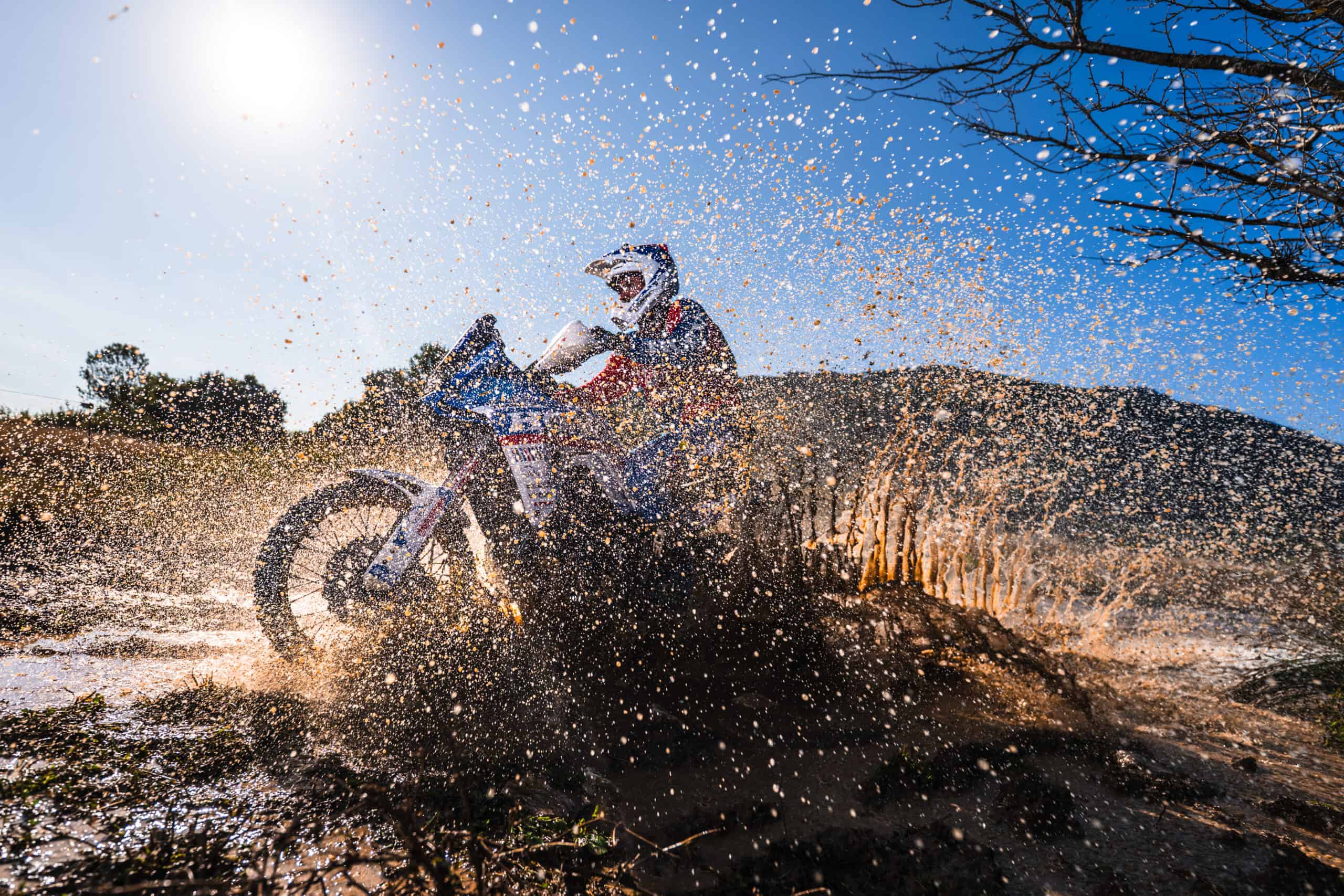 Rally rider splashing through water on a rocky Dinaric track